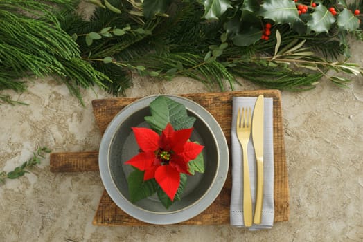 Christmas place setting with golden silverware, holly and poinsettia