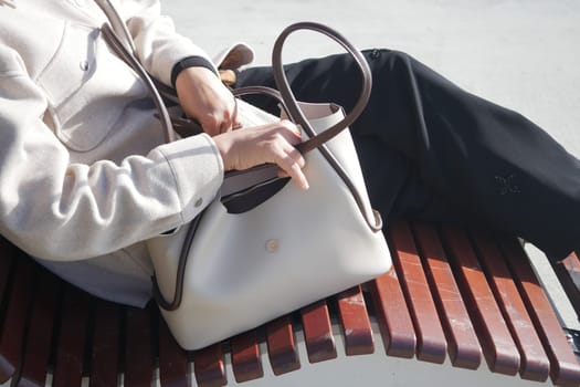 A person enjoys a sunny day while sitting on a wooden bench.