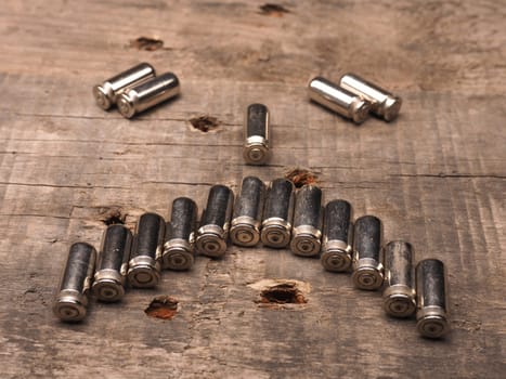 Unhappy face of bullets on a wooden background