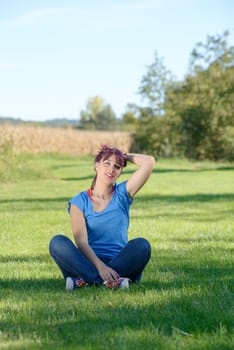 beautiful young woman sitting in the grass in the countryside