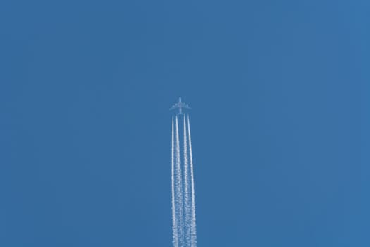 Airplane flying at high altitude contrails against a dark blue sky...