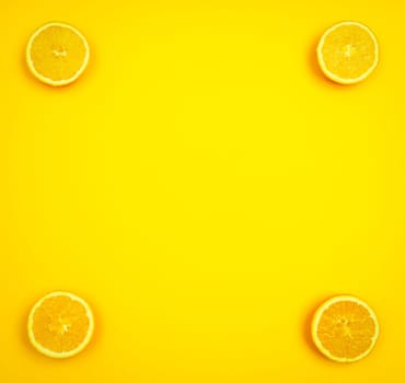 Orange slices in the corners of a yellowish background with copy space