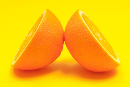 Fresh half orange citrus fruit on yellow background