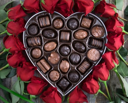 Heart shaped box of chocolates surrounded by roses.