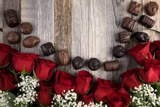 Red roses, baby's breath, and chocolates on wooden backbround with copy space.