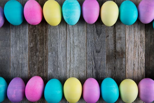 Frame of colorful Easter eggs on wooden background with copy space.