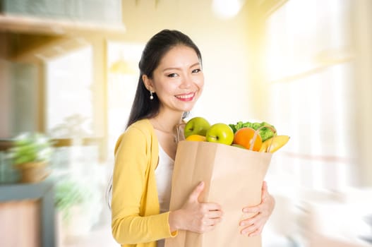 Young Asian woman hand holding shopping paper bag filled with fruits and vegetables in market store or cafe .