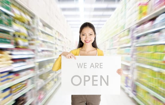 Young Asian woman hand holding "we are open"" sign board in market or department store."