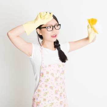 Young Asian woman with rubber gloves cleaning house with brush.