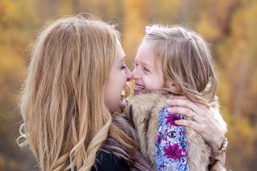 Mother and daughter playing nose to nose in autumn nature