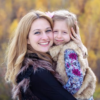 Happy mother hug her daughter in autumn background