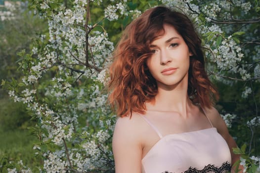 Free Happy Woman with Gorgeous Red Hair Enjoying Nature. Beauty Young Girl Outdoor in Spring Garden. Freedom concept. Healthy Smiling Girl over Green Flowers Nature Background. Apple-trees in Blossom