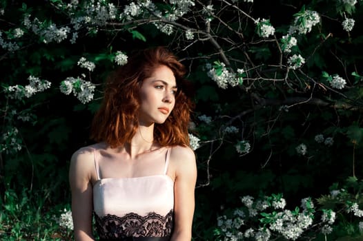 Free Happy Woman with Gorgeous Red Hair Enjoying Nature. Beauty Young Girl Outdoor in Spring Garden. Freedom concept. Healthy Smiling Girl over Green Flowers Nature Background. Apple-trees in Blossom
