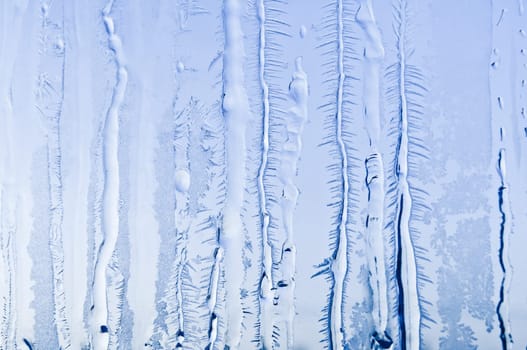 Melted and frosted ice pattern on frosty window glass in winter