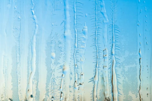 Melted and frosted ice pattern on frosty window glass in winter