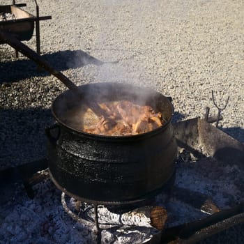 ACHAO, CHILE - FEBRUARY 6, 2016: Meat cooking in caldron at the Muestras Gastronomicas 2016 Gastronomy Show in Achao, Chiloe Archipelago, Chile (Selective Focus, Focus into the caldron)