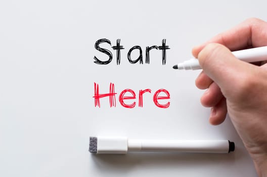 Human hand writing start here on whiteboard