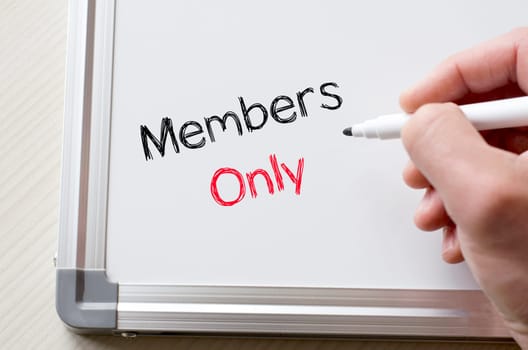 Human hand writing members only on whiteboard