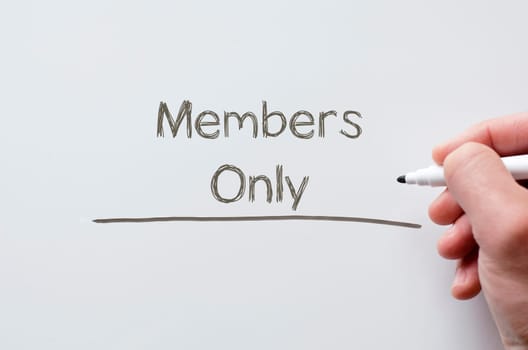 Human hand writing members only on whiteboard