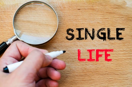 Human hand over wooden background and single life text concept