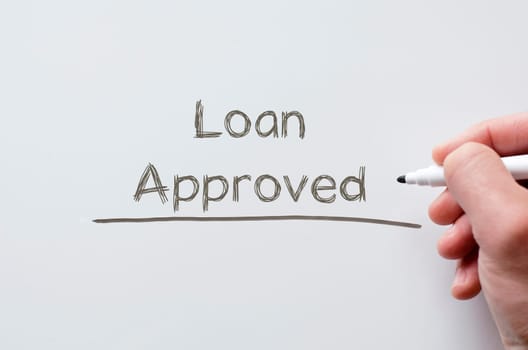 Human hand writing loan approved on whiteboard