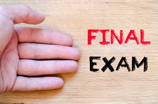 Human hand over wooden background and final exam text concept