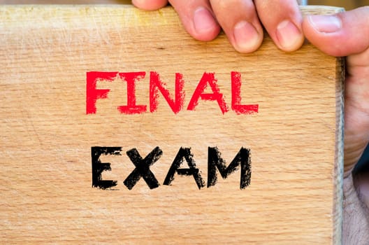 Human hand over wooden background and final exam text concept