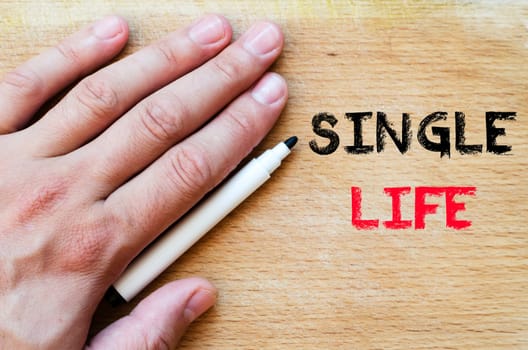 Human hand over wooden background and single life text concept