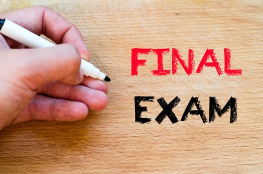Human hand over wooden background and final exam text concept