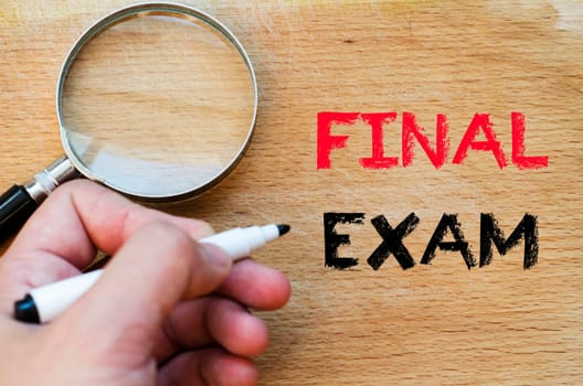 Human hand over wooden background and final exam text concept