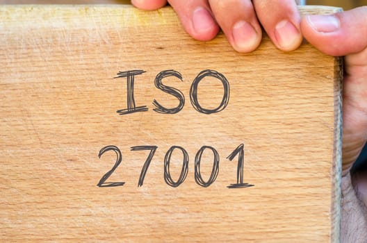 Human hand over wooden background and iso 27001 text concept