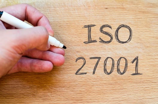 Human hand over wooden background and iso 27001 text concept