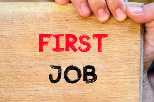 Human hand over wooden background and first job text concept