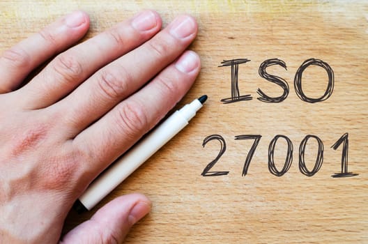 Human hand over wooden background and iso 27001 text concept