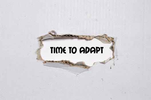 The word time to adapt appearing behind torn paper