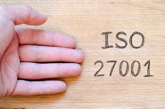 Human hand over wooden background and iso 27001 text concept