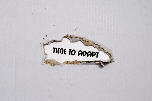 The word time to adapt appearing behind torn paper