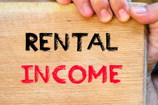 Human hand over wooden background and rental income text concept
