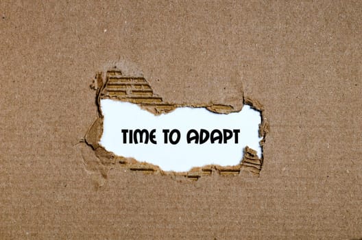 The word time to adapt appearing behind torn paper