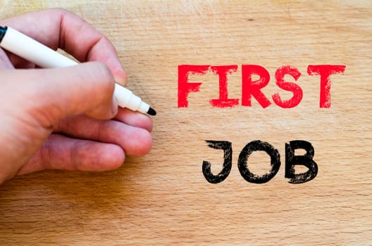 Human hand over wooden background and first job text concept