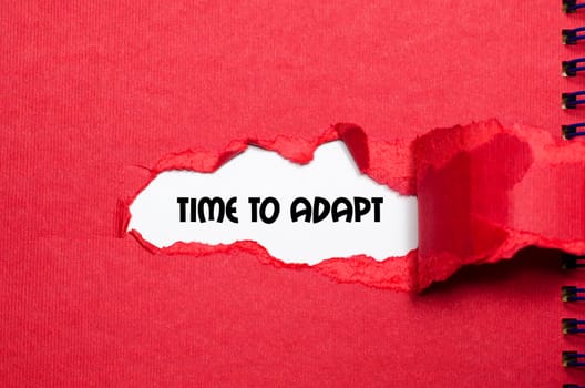 The word time to adapt appearing behind torn paper