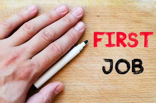 Human hand over wooden background and first job text concept