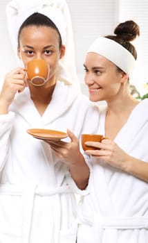 relax in the beauty salon,coffee with a friend. coffee,relaxation and beauty women in a beauty salon. two women in living room wellness dressed in white robes with cups of coffee