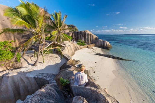 Female traveler emjoying amazing view of beautifully shaped granite boulders at picture perfect tropical Anse Source d'Argent beach, La Digue island, Seychelles.