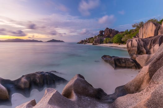 Beautifully shaped granite boulders and a dramatic sunset at picture perfect tropical Anse Source d'Argent beach, La Digue island, Seychelles.