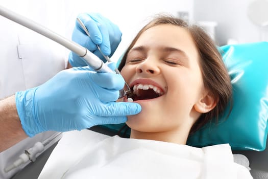 a child in a dental chair during a dental treatment. treatment of tooth loss,a child at the dentist. a dental office,a child in a dental chair. tooth treatment,the dentist cleans the cavity
