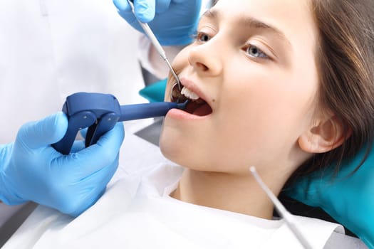 a child in a dental chair during a dental treatment. treatment of cavities,baby at dentist. tooth decay in children,oral hygiene. lacing teeth,child at the dentist. dental office,child in the dental chair\nlight-sensitive seal,baby in the dentist's office