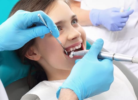 a child in a dental chair during a dental treatment. treatment of tooth loss,a child at the dentist. a dental office,a child in a dental chair. tooth treatment,the dentist cleans the cavity