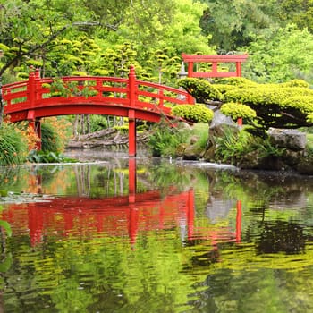Red bridge over water in Japanese garden