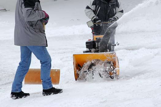 Snow clearing in winter. Two men clear snow from the road. Snow clearing with snow blower and snow shovel
